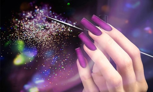 Hand with a beautiful manicure and a brush on a purple bokeh background. Nail design. Extended