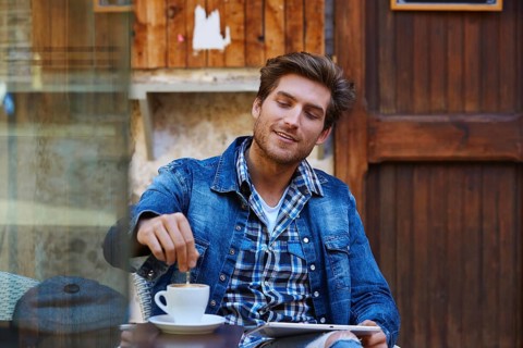 Young man with tablet pc touch in an cafe outdoor having some coffe cup