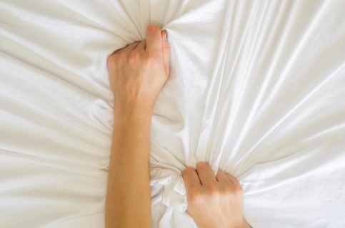 Hand sign orgasm of woman on white bed, Hand of female pulling white sheets in ecstasy, feeling and