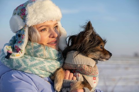 Close-up on the face of a girl looking towards the sun. The girl, wearing a cap and jacket, is