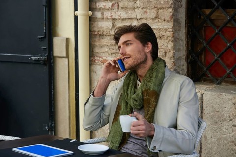 Young man talking smartphone phone in an cafe outdoor sitting having some coffe