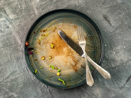 Dirty dish and silverware cutlery on gray background, top view or flat lay. Empty dirty craft plate