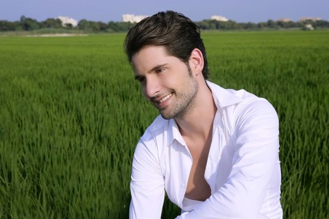 Young man outdoor happy relaxed on green rice field meadow