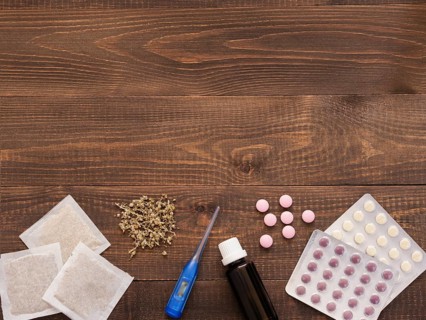 Tablets, drops, herbals and thermometer on a dark wooden background with copy space. Herbal