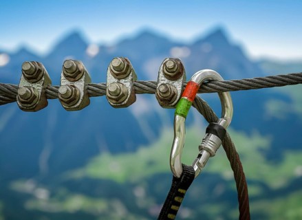 A Climbing Carabiner In The Foreground Of The Scenic Swiss Alps