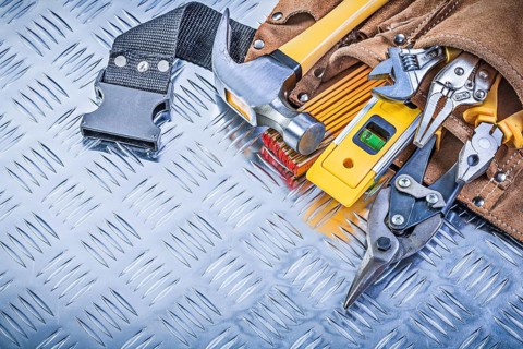 Collection of construction tooling in tool belt on corrugated metal background maintenance concept