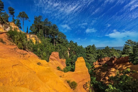 Multi-colored ocher outcrops - from yellow to orange-red. Green trees create a beautiful contrast