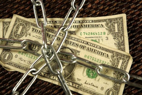 One Dollar notes in chains studio shot over brown background