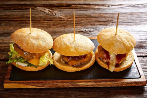 Burger in a row on a slate board and wood table