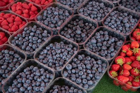 Fresh ripe blueberries and strawberries in a box for sale in a fruit market. Organic fruit, healthy