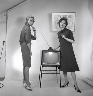 Television in the 1950s. Two young women are standing dressed in a typical 50s dress beside a
