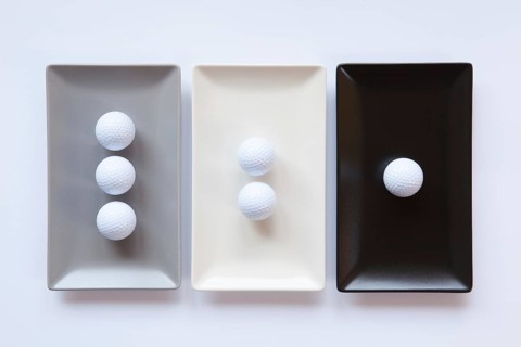 Different ceramic dishes with golf balls on over white background, rectangle dish
