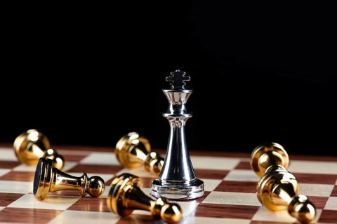 Silver king chess defeats gold pawns on wooden chessboard. Intellectual duel and tactical battle in
