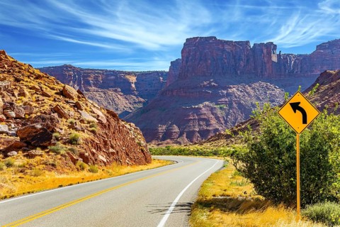 Wide asphalt highway among picturesque hills and rocks of bizarre shapes. The grandiose landscapes