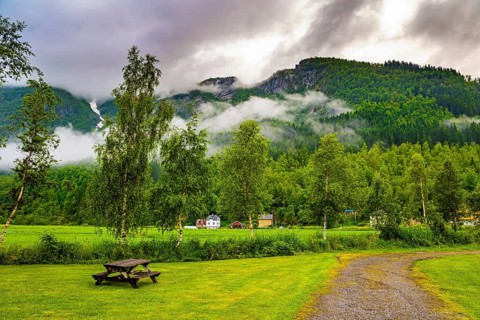 Rain-wet dirt road crosses a valley. Jostedalsbreen Park. Heavy clouds covered the sky. Valley