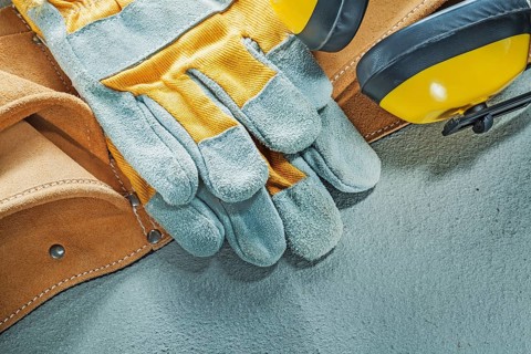 Set of leather tool belt protective gloves earmuffs on concrete background