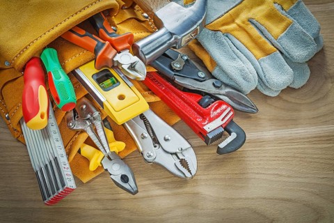 Tools in leather building belt on wooden board top view