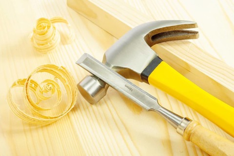 Claw hammer and chisel on wooden board