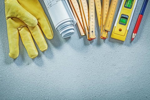Protective gloves construction level wooden meter blueprints pencil on concrete background building