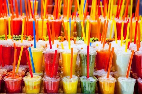 Colorful natural fresh fruits juice glasses with straw stacked in rows