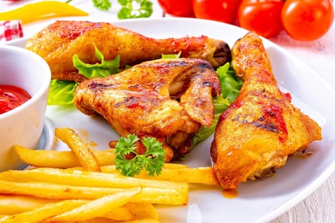 Grilled chicken wings, legs, chips and vegetables