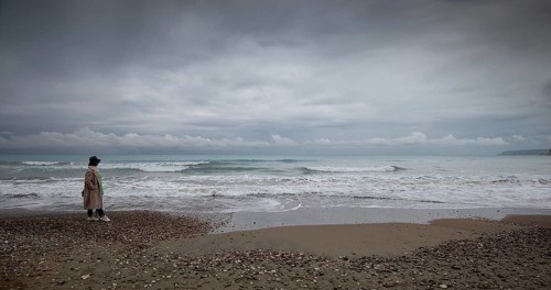 One woman walking on the coast beach. Stormy sky windy waves. Paphos Cyprus