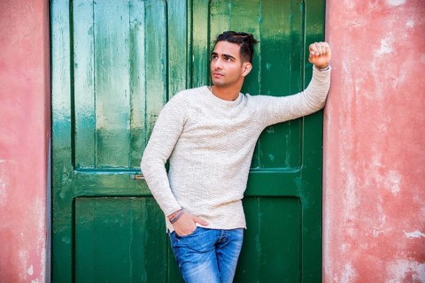 Elegant young man leaning against old wall and green door
