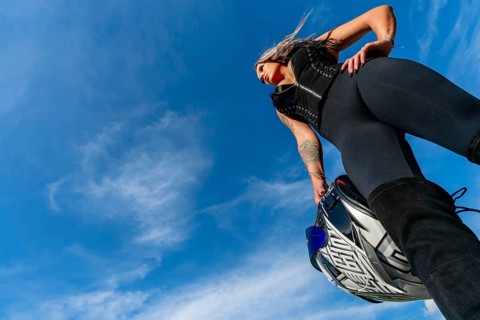A stunning woman strikes a confident pose beside her high-performance motorcycle. With a fierce