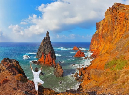 The woman ashore in a white suit for yoga carries out a pose Tree. Atlantic storms. Colorful