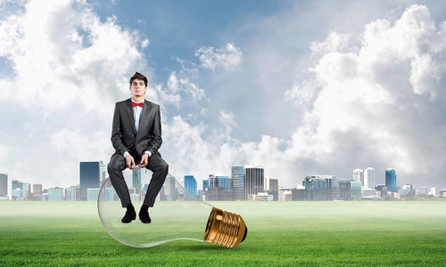 A businessman with glasses sits on a light bulb. concept of creativity in business
