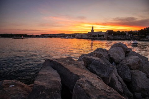Town on a coast, with a stone fortification a harbour with a view of the sunset. Landscape photo of