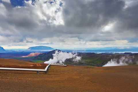 Krafla Lake neighborhood. Summer Iceland. Steam rises above the hot ground. Pipeline to transport
