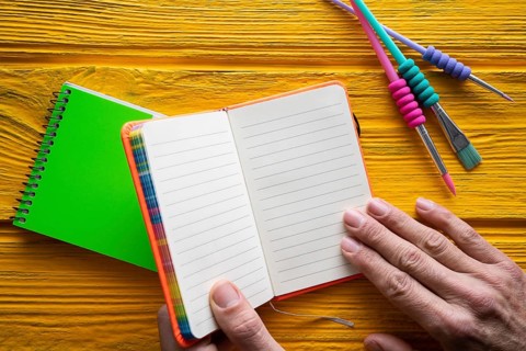 Back to school supplies notebook an brushes vivid colorful neon teachers hand