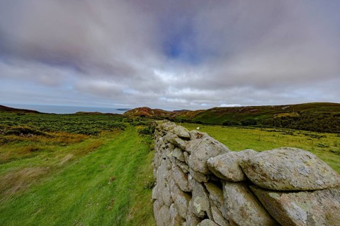Hilly landscape with green meadows and stone wall, dry stone wall on the edge of Snowdonia National