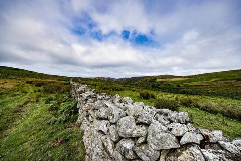 Hilly landscape with green meadows and stone wall, dry stone wall on the edge of Snowdonia National