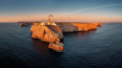 Portuguese coast with a lighthouse in the rays of the setting sun, Cabo De Sao Vincente on sunset