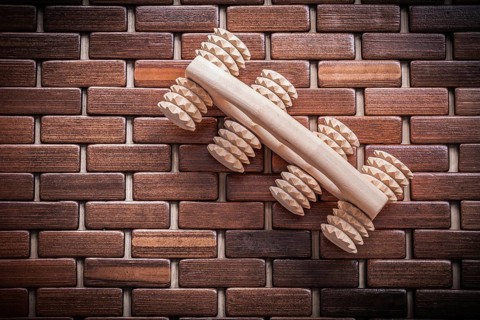 Wood massager with handle on textured wooden mat healthcare concept