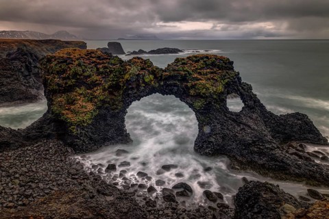 Rocky shore with a surf with foam on the water at Gatklettur
