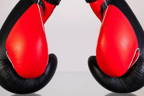 Red and black boxing gloves on a glass table isolated on white background