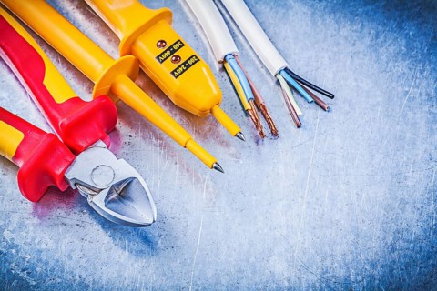 Yellow electrical tester wires wire cutter on metallic background electricity concept