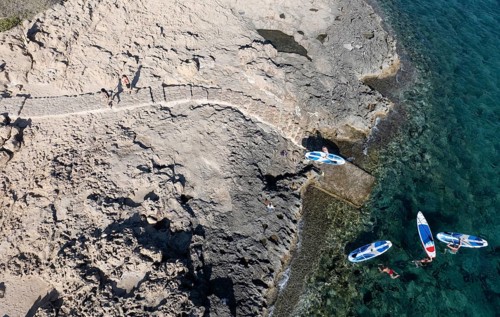 Done view of unrecognized people kayaking in the sea. People active, healthy lifestyle. Cape Grego