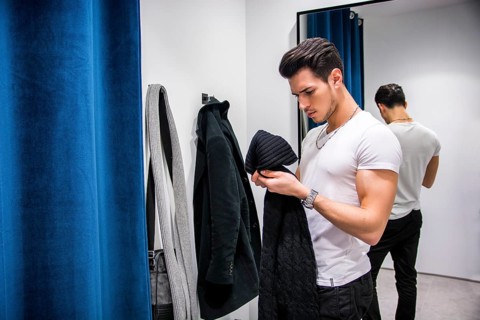 Young Handsome Man Trying on Clothes in Clothing Store', s Changing Room in Front of a Mirror or