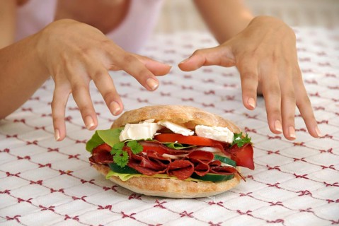 Hungry girl hands over appetising big sandwich with ham and cheese