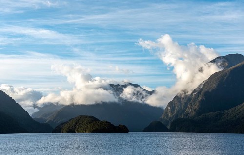 Sun rising over Doubtful Sound, Clouds hanging low on the mountains, South Island of New Zealand