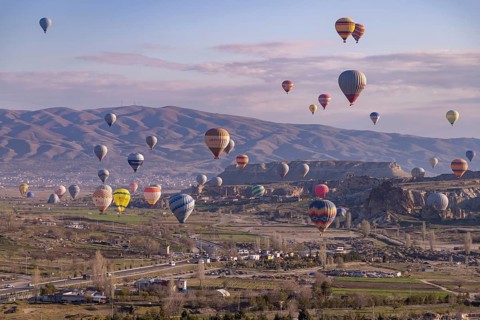 A picture of colorful hot air balloons flying over the landscape of Goreme Historical National Park