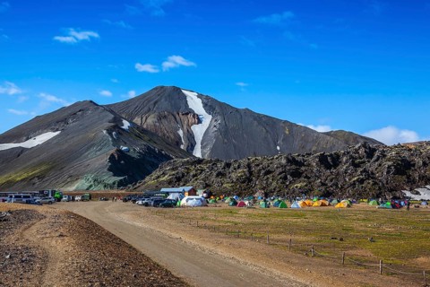 Rhyolite mountains surround the flat valley of National Park Landmannalaugar. Big tourist camp is