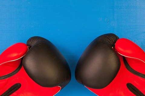 Red and black boxing gloves on a blue wooden table