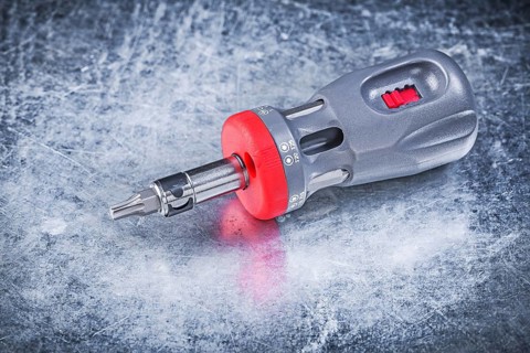 Reversible screwdriver on metallic background construction concept