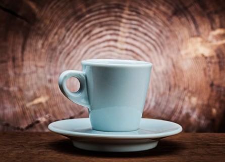 White ceramic coffee cup on vintage wood background with cross cut of tree trunk
