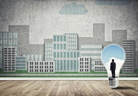 Businessman inside light bulb against city drawn concept